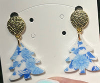 Timeless with a touch of festive flair, these Blue and White Toile Christmas Tree Dangle Earrings bring elegance to your holiday look. Featuring a classic toile pattern in blue and white, topped with a shiny blue mirrored bow, they’re the perfect accessory for a sophisticated seasonal statement. Lightweight, hypoallergenic, and nickel-free for all-day comfort.