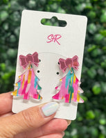 Colorful bow earrings on a white card held by a hand with a blurred green background