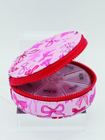 Pink pill organizer with bow pattern on a white background