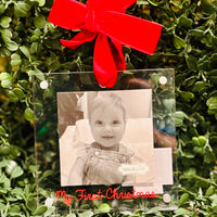 Clear photo frame with a red bow and black and white photo of a baby on green foliage.