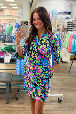 Print | Hibiscus Nights — navy base with bold tropical floral in pink, purple, teal, and green
Neckline | Split V-neckline
Sleeves | Quarter sleeves with rolled cuffs
Silhouette | Shift dress
Length | Above the knee
Fabric | 60% Nylon, 40% Spandex — lightweight with a comfortable stretch
Sun Protection | UPF 50+
Brand | Aryeh