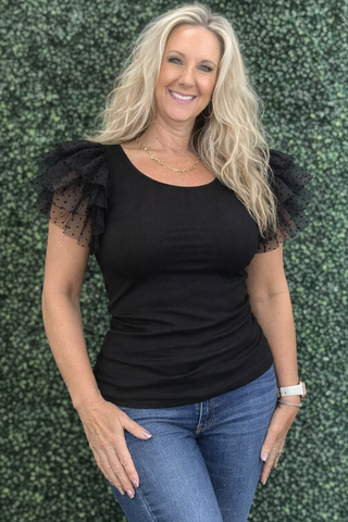 Black ribbed knit top with polka dot mesh ruffle sleeves and slim fit silhouette.