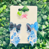 Classic blue and white toile ornament dangle earrings with a mirrored blue bow top. A classy holiday accessory that’s hypoallergenic and nickel-free.