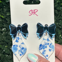 Classic blue and white toile ornament dangle earrings with a mirrored blue bow top. A classy holiday accessory that’s hypoallergenic and nickel-free.

