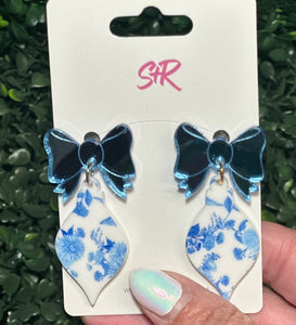 Classic blue and white toile ornament dangle earrings with a mirrored blue bow top. A classy holiday accessory that’s hypoallergenic and nickel-free.

