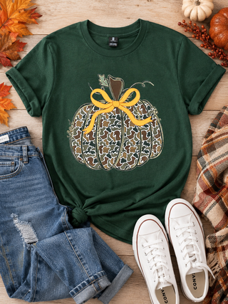 Camo Pumpkin with an orange bow on the stem. Printed on a dark green gildan tee. Front print graphic tee