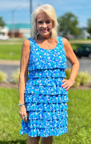 Feminine, flirty, and made for sunny days. The Lulu-B Cha Cha Dress in SBDY features a classic blue background with delicate white florals — charming ruffles on the front and back, a scoop neckline, and a clean straight hemline give it a romantic, effortlessly pretty silhouette that flatters every shape and size.