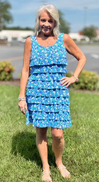 Feminine, flirty, and made for sunny days. The Lulu-B Cha Cha Dress in SBDY features a classic blue background with delicate white florals — charming ruffles on the front and back, a scoop neckline, and a clean straight hemline give it a romantic, effortlessly pretty silhouette that flatters every shape and size.