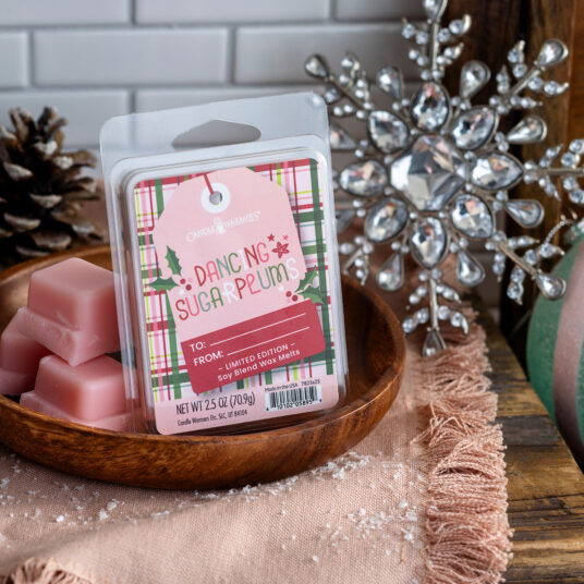 Pink wax melts in a wooden bowl with a decorative tag on a festive background