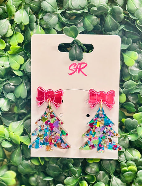 Add a pop of color to your holiday look with these Blue Shred Confetti Acrylic Christmas Tree Dangle Earrings! Featuring a vibrant blue confetti tree and topped with a playful pink mirrored bow, this pair brings a fresh, fun twist to classic Christmas style. Lightweight, hypoallergenic, and nickel-free—perfect for merry-making all season long.

