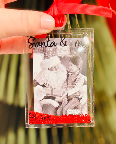 Glitter Acrylic Photo Ornament - Santa & Me 
Capture a memory and sparkle all season long with our Acrylic Glitter-Filled Photo Ornament! Designed to hold a wallet-size photo, this clear acrylic ornament is filled with festive glitter that adds the perfect holiday shimmer. A thoughtful keepsake for your own tree or a heartfelt gift for someone special.

