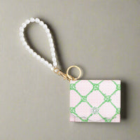 Lilly Pulitzer Butterfly Trellis snap card case with a scalloped envelope opening, card slots, a cash pocket, gold hardware, and a pearl wrist strap.
