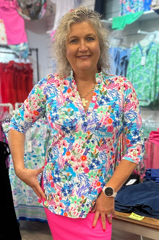 Lush, nature-inspired, and made for wherever the day takes you. The Lulu-B V-Neck Travel Tunic in MCDR features a beautiful tropical floral and water scene with charming dragonfly details — a stunning V-neckline with button placket and button details, 3/4-length sleeves, straight hemline with side slits, and a smoothing nylon blend that skims your curves just right give it a polished, resort-ready look that transitions effortlessly from travel days to warm-weather outings. UPF 50+ protection and pre-shrunk 