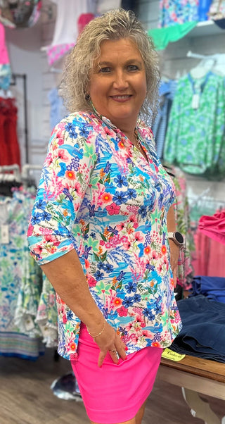 Lush, nature-inspired, and made for wherever the day takes you. The Lulu-B V-Neck Travel Tunic in MCDR features a beautiful tropical floral and water scene with charming dragonfly details — a stunning V-neckline with button placket and button details, 3/4-length sleeves, straight hemline with side slits, and a smoothing nylon blend that skims your curves just right give it a polished, resort-ready look that transitions effortlessly from travel days to warm-weather outings. UPF 50+ protection and pre-shrunk 