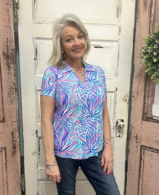 Short sleeve collared top with pineapples on it and shades of purple, blue, white and hot pink.