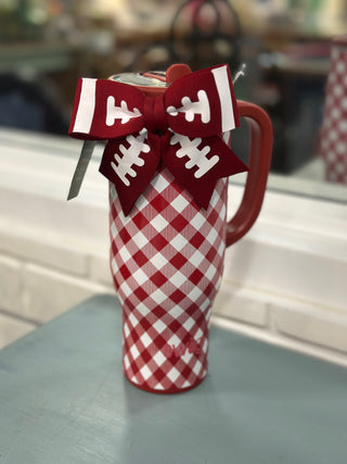 A red and white gingham patterned insulated mug with a red handle, decorated with a red and white bow featuring football lace details