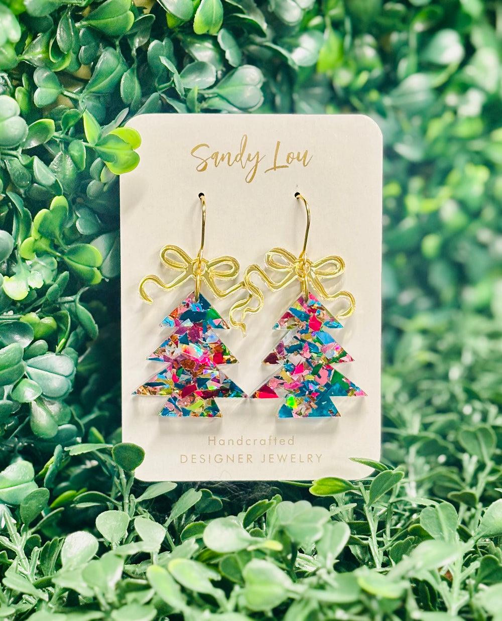 Add a pop of festive cheer to your holiday style with these handcrafted Christmas tree earrings! Featuring vibrant confetti-style acrylic in a dazzling rainbow of colors, each shimmering tree is topped with a gold-tone ribbon for the perfect festive finishing touch.