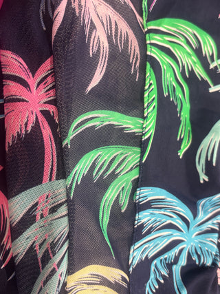 Close-up of a tropical palm tree print fabric with vibrant green, pink, blue, and yellow leaves on a navy background.