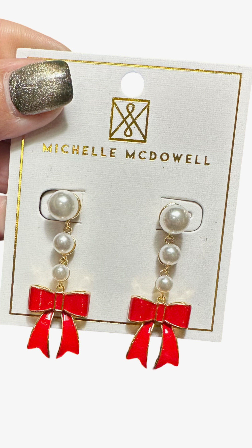 Pearl earrings with red bows on a Michelle McDowell branded card.