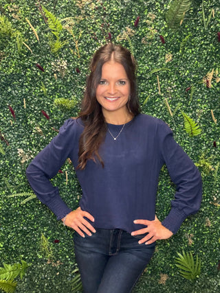 Reach for this elevated navy long sleeve top when you want everyday comfort with a little more polish. Its soft brushed feel, relaxed silhouette, and subtle sleeve detail make it an easy choice for workdays, weekend plans, and everything in between.

Key Details
Fit | Relaxed silhouette
Fabric Feel | Soft brushed rayon, polyester, and spandex blend
Neckline | Classic crew neckline
Sleeves | Long puff sleeves with smocked cuffs
Color | Navy