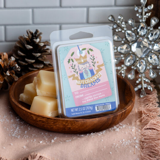 Wax melts in a wooden bowl with packaging labeled 'Nutcracker Dreams' on a decorative background.