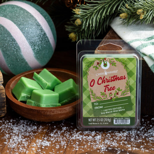 Green wax melts in a wooden bowl with a 'O Christmas Tree' wax melt package on a festive background.