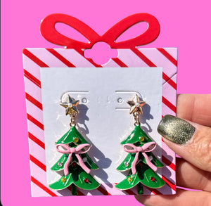 Add a festive touch to your holiday look with the Pink Bow Christmas Tree Earrings. These charming post-back earrings measure 2" tall x 1" wide, featuring a playful pink bow atop a classic Christmas tree design. Lightweight and cheerful, they’re perfect for celebrating the season in style.