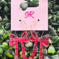 Holiday-ready red, white, and black acrylic bow dangle earrings on a gold hoop. Lightweight, hypoallergenic, and nickel-free—perfect for festive styling.