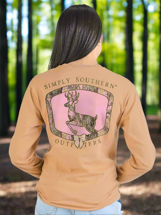 Woman wearing a tan long-sleeve shirt with a Simply Southern Outfitters logo on the back.
