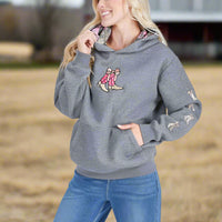 Woman wearing a gray hoodie with a graphic design on a light gray background