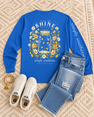 Simply Southern Long Sleeve Tee 
Printed on a bright blue tee 
Features the saying "Let your light shine for all to see" 
Graphic Detail: back printed design featuring a mason jar filled with fireflies surrounded by flowers.