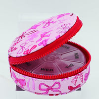 Pink pill organizer with bow pattern on a white background