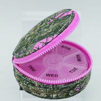 Pink and green pill organizer with floral pattern on a white background