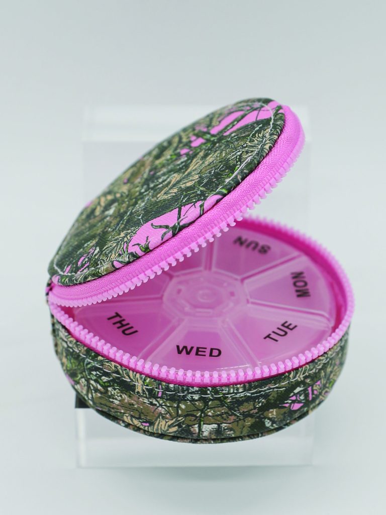 Pink and green pill organizer with floral pattern on a white background