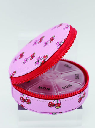 Pink pill organizer with cherry design on a white background