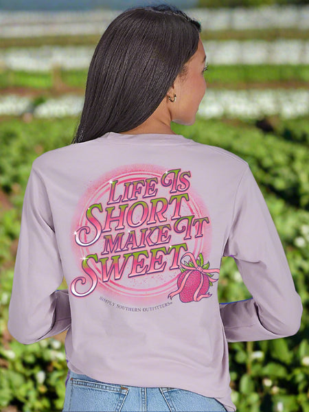 Person wearing a light purple long-sleeve shirt with 'Life is Short, Make It Sweet'