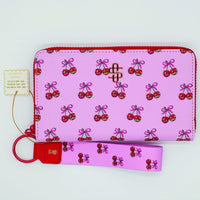 Pink wallet with cherry pattern and matching keychain on a white background