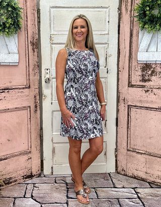 The Lulu-B Sleeveless Travel Dress in the JTBW print features a striking black and white pattern with hints of hot pink and hidden animals woven throughout — soft, stretchy fabric, a flattering scoop neckline, and UPF 50 protection make it the perfect dress for vacation, sunny day outings, or anywhere you want to look polished without trying too hard.