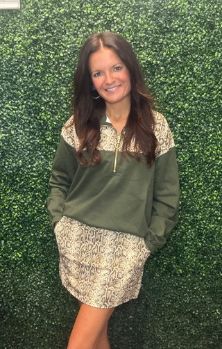 olive green and snakeskin print quarter-zip pullover sweater and a matching snakeskin print mini skirt.