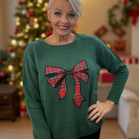 Stay cozy and stylish in this green sweater featuring a charming tartan bow.