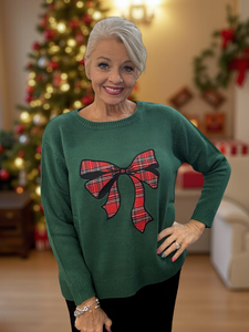 Stay cozy and stylish in this green sweater featuring a charming tartan bow.