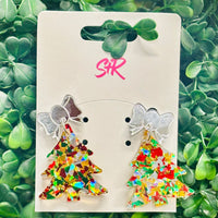 Festive confetti Christmas tree dangle earrings with red, green, silver, and gold shimmer, topped with a silver mirrored bow. Hypoallergenic and nickel-free.