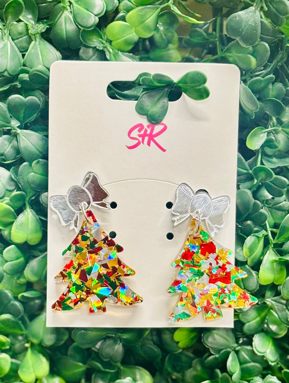 Festive confetti Christmas tree dangle earrings with red, green, silver, and gold shimmer, topped with a silver mirrored bow. Hypoallergenic and nickel-free.