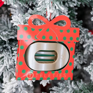 Design | Flat round hair clip with a low-profile back for comfort against car seats, couches, and pillows.
Hold | Bendable teeth flex to the hair for a secure hold without pulling or snagging.
Material Feel | Lightweight, flexible, and nearly unbreakable for everyday wear.
Hair Types | Designed to work on all hair types.
Packaging | Present-shaped ornament box with festive polka dots, a red bow, and a hanging loop.
Includes | One flat round hair clip in ornament packaging.